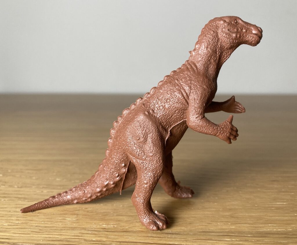 Upright Marx Iguanodon dinosaur toy in a monochrome chocolate brown colour.