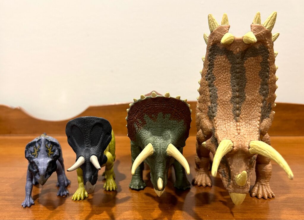Triceratops toy action figure by Mattel next to three other horned dinosaur actions figures