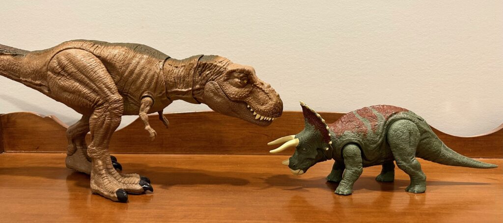 Triceratops toy action figure by Mattel next to a T. rex toy action figure by Mattel